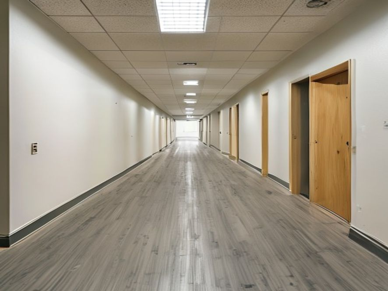 Heavy-duty stone-speckle commercial vinyl flooring fitted with welded seams in a small office corridor.